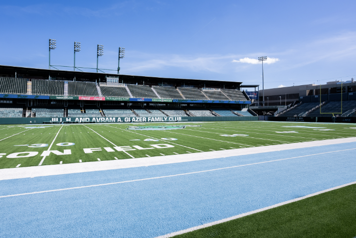 Empty stadium with a green sports field and a light blue running track.
